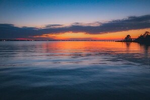 A calm waterfront at sunset with a pier extending into the water. - Oak Shores 157 | Just a Short Walk to the Beach! (Biloxi)