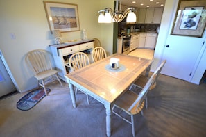 A dining area with a table, chairs, a chandelier, and kitchen cabinets in the background.