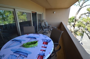 A balcony with a table, chairs, and a view of trees and buildings.