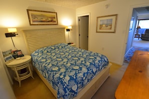 A bedroom with a bed, bedside table, lamp, and framed pictures on the wall.