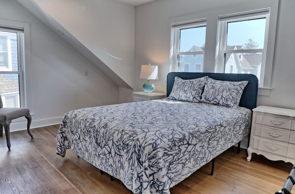 Une chambre à coucher avec un lit, une table de chevet, une chaise et des fenêtres.