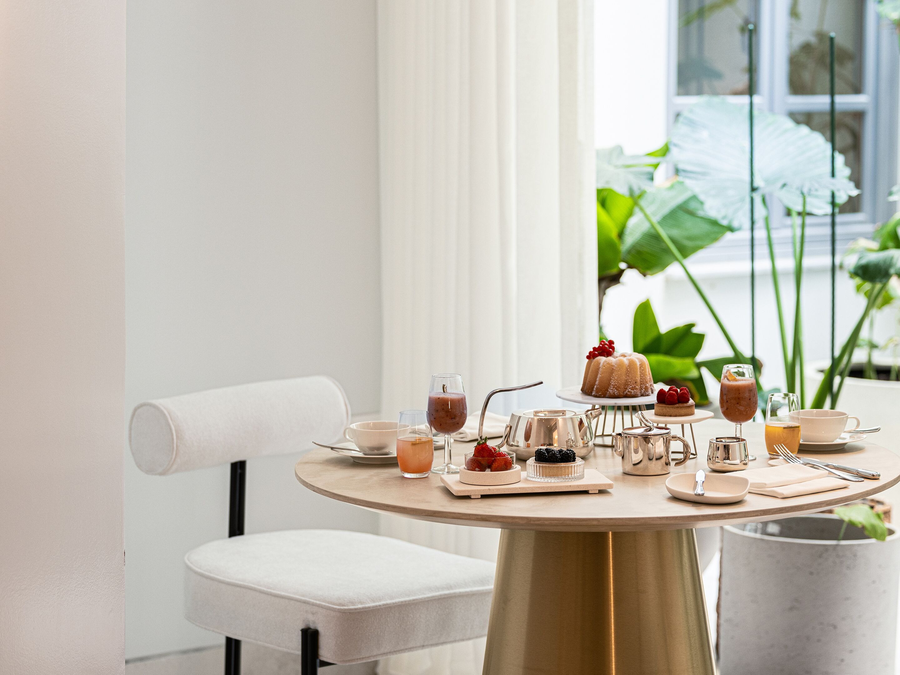 A round table with a white chair, a small white table, and a metal pitcher.