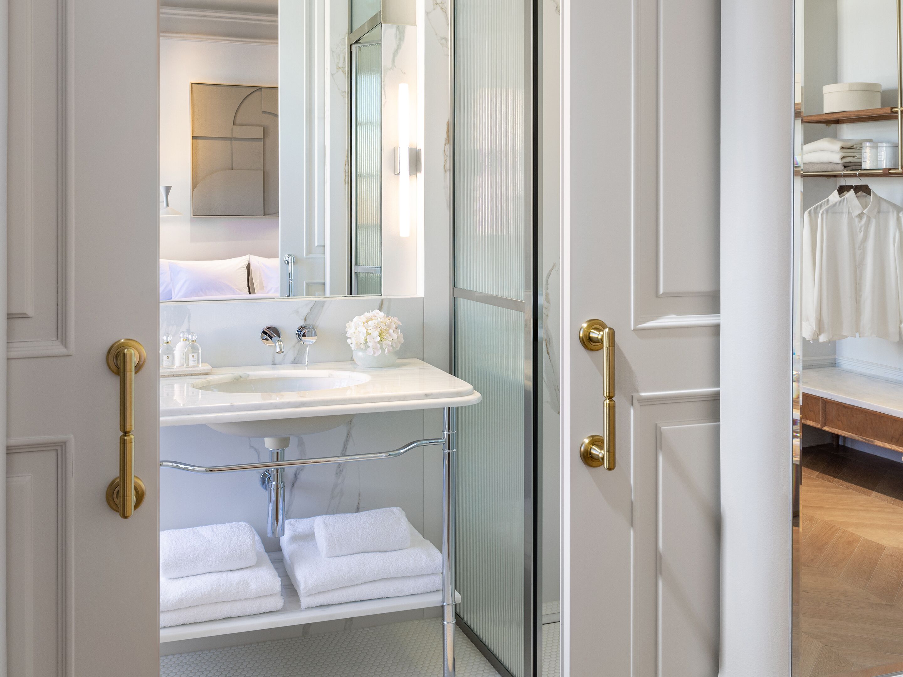 Un baño moderno con lavamanos, espejo y toallero blancos.