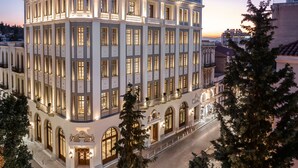 Un hotel de varios pisos con fachada clásica, amplias ventanas y un patio central.