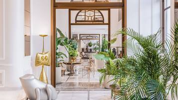 A spacious lobby with a marble floor, a large potted plant, and a unique sculpture.