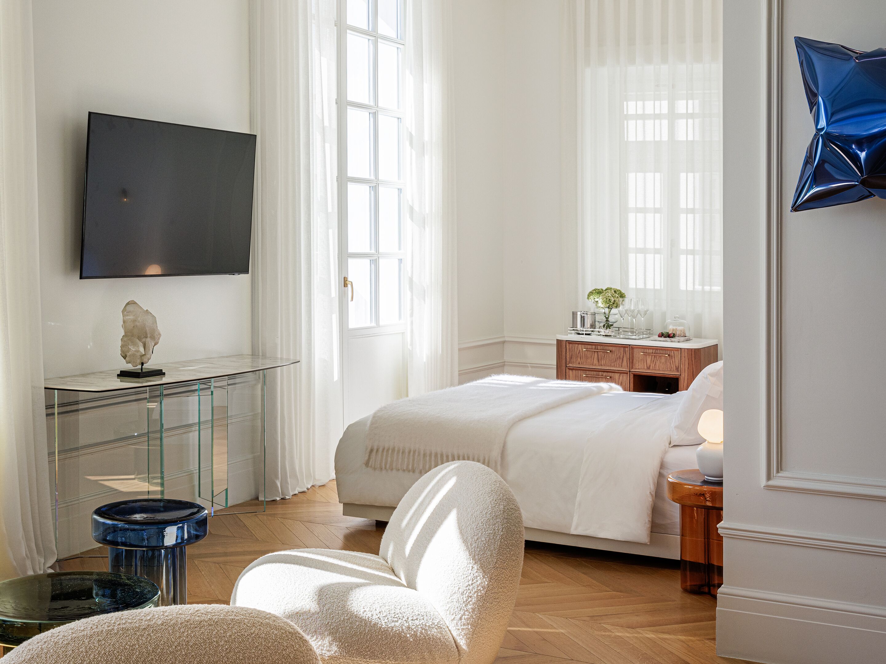 A modern hotel room with a bed, a desk, a chair, and a TV.