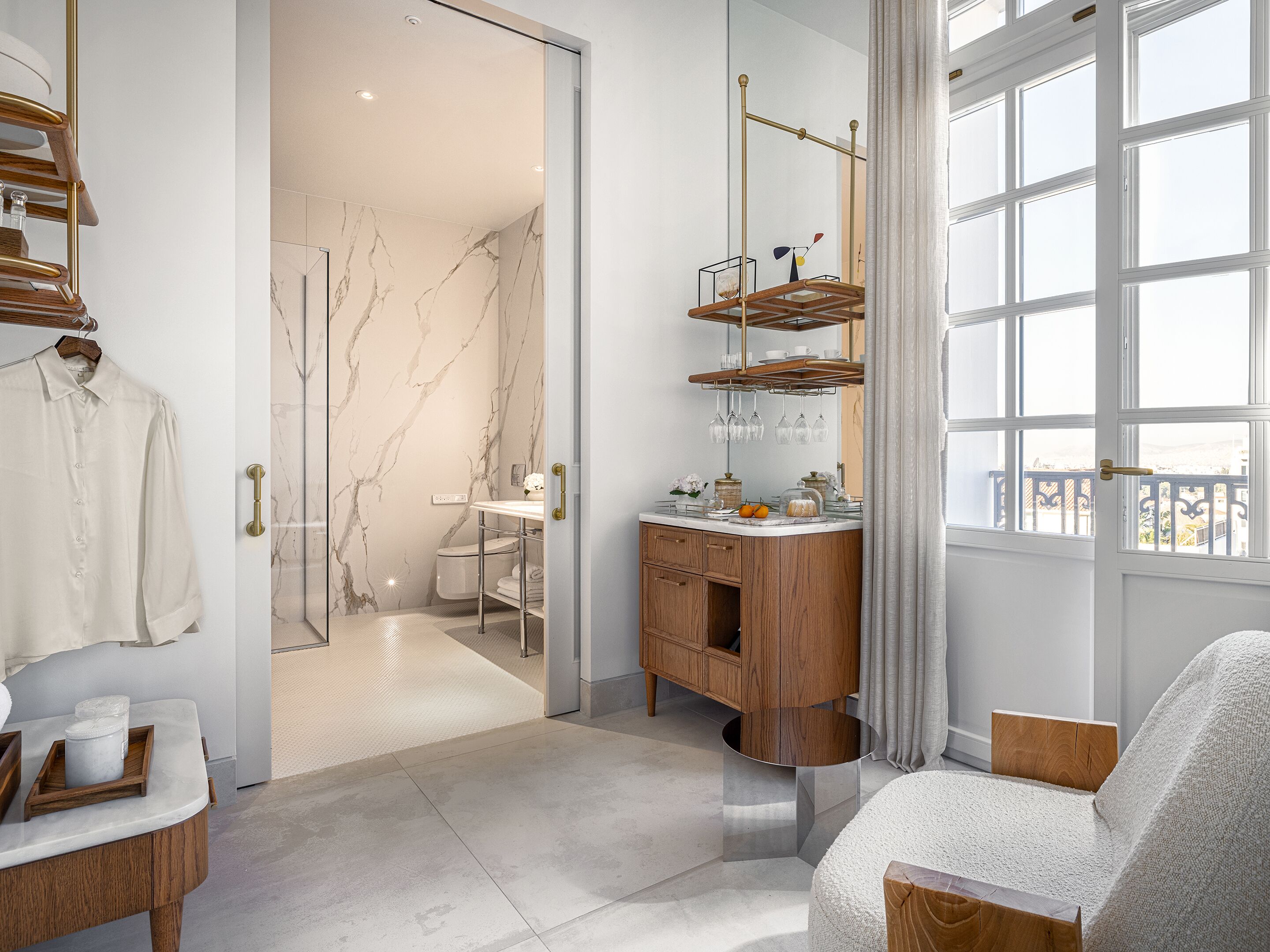 A modern bathroom with a marble wall, a wooden vanity, and a glass shower enclosure.