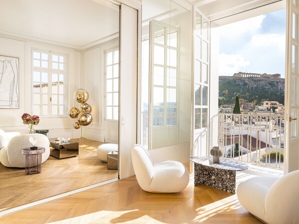 Een ruime kamer met een grote spiegel, uitzicht op een stadsbeeld en een moderne witte bank.
