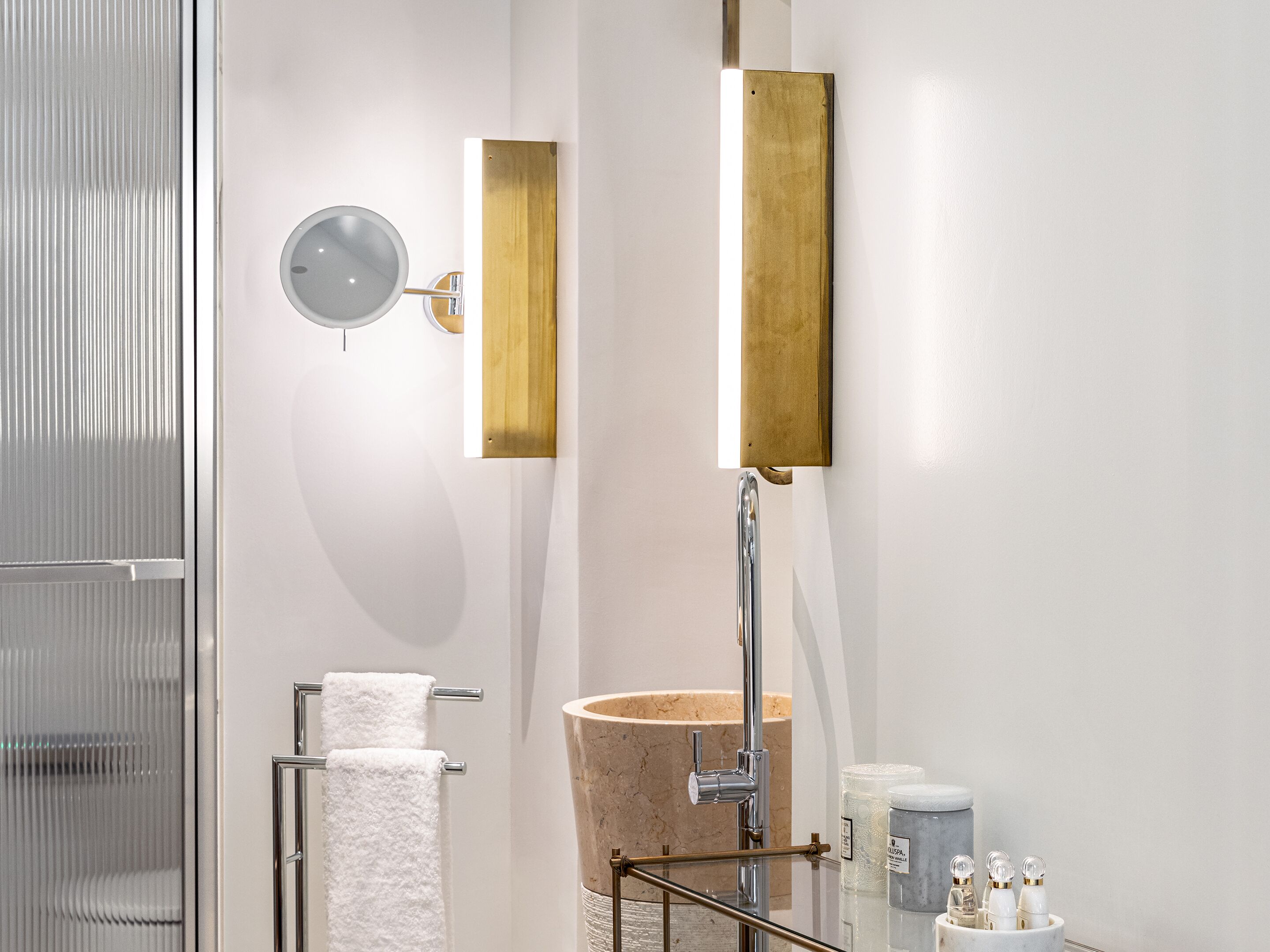 A modern bathroom with a glass shower enclosure, a freestanding bathtub, a wall-mounted mirror, and a towel rack.