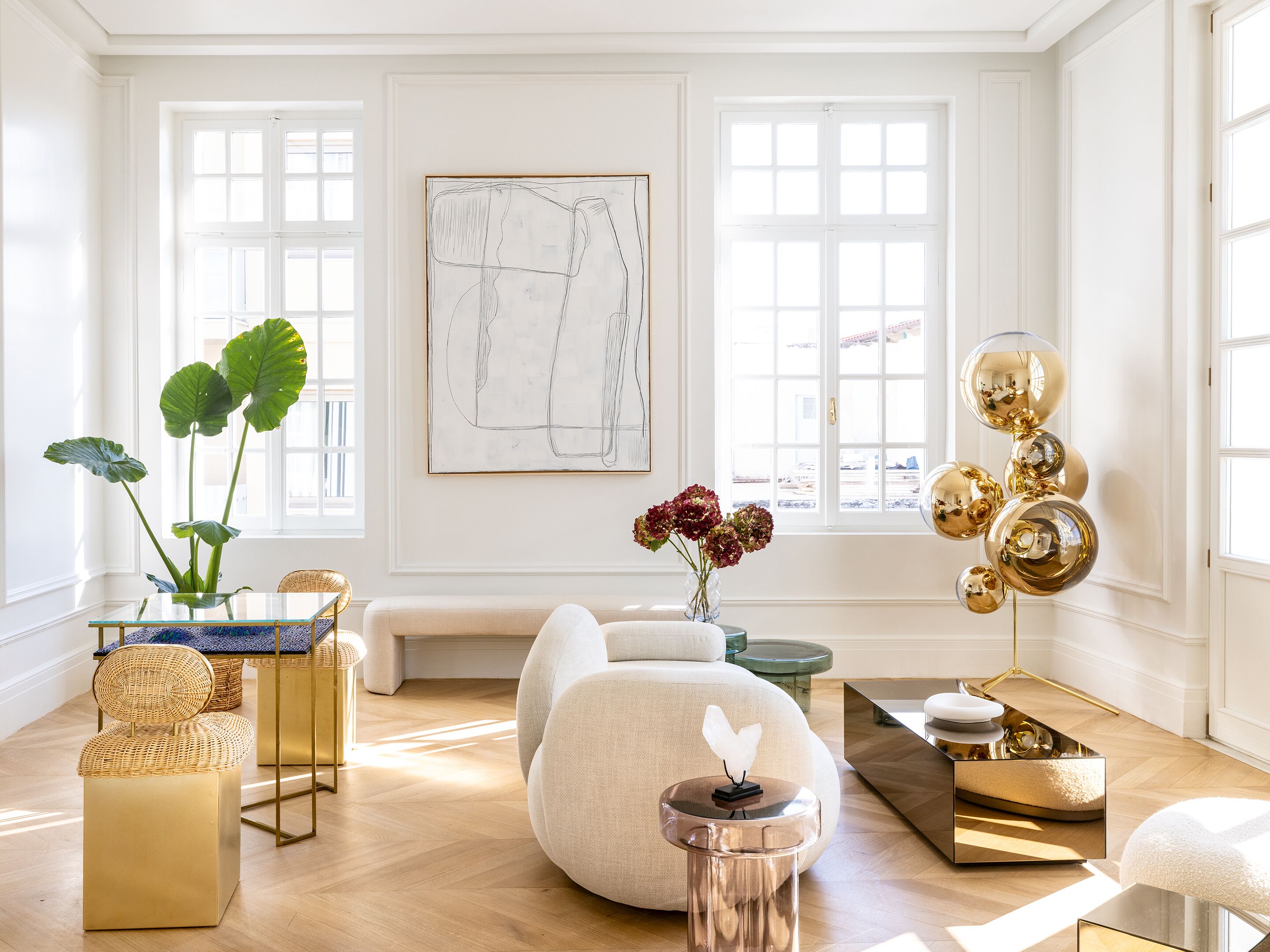 A modern living room with a glass coffee table, a sofa, and a decorative plant.