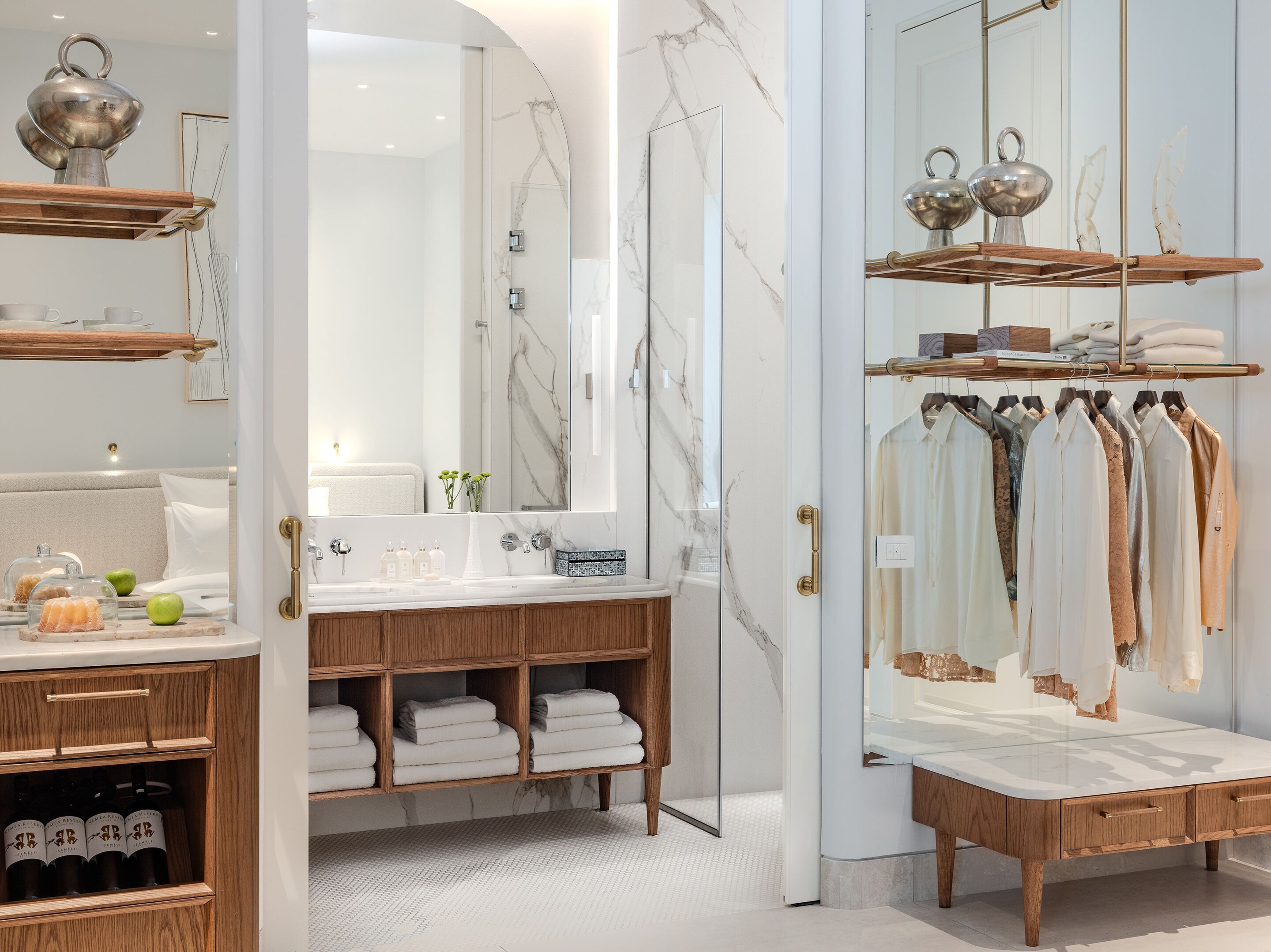 A modern bathroom with a marble vanity, a glass shower enclosure, and a clothing rack.