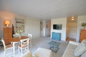 Un salon comprenant une table à manger, des chaises, un canapé, un téléviseur et une commode bleue.