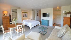 Une chambre à coucher comprenant un lit, une télévision, une commode et un coin repas avec une table et des chaises.