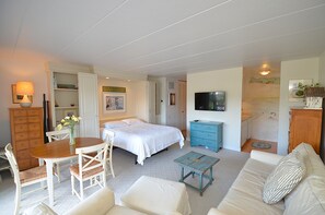Ein Schlafzimmer mit Bett, Fernseher, Kommode und Essecke mit Tisch und Stühlen.