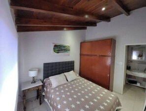 Quarto com cama, guarda-roupa, mesa de cabeceira e espelho.
