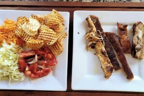 Duas travessas brancas com alimentos, incluindo waffles, carne e legumes.