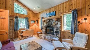 A cozy cabin interior with wooden walls, a stone fireplace, a dining table, and a comfortable seating area. - Stargazer Chalet in Carnelian Bay (Carnelian Bay)
