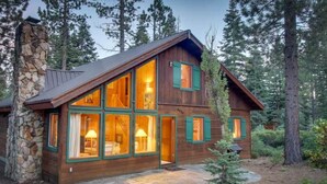 A wooden cabin with large windows, a stone chimney, and a stone foundation. - Stargazer Chalet in Carnelian Bay (Carnelian Bay)