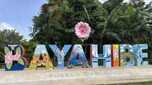 A colorful sign with the word "BAYAHUE" and "PUEBLO EN ANTAR" beneath it, surrounded by lush greenery.