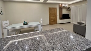 A modern living room with a dining area, a TV, and a sofa.