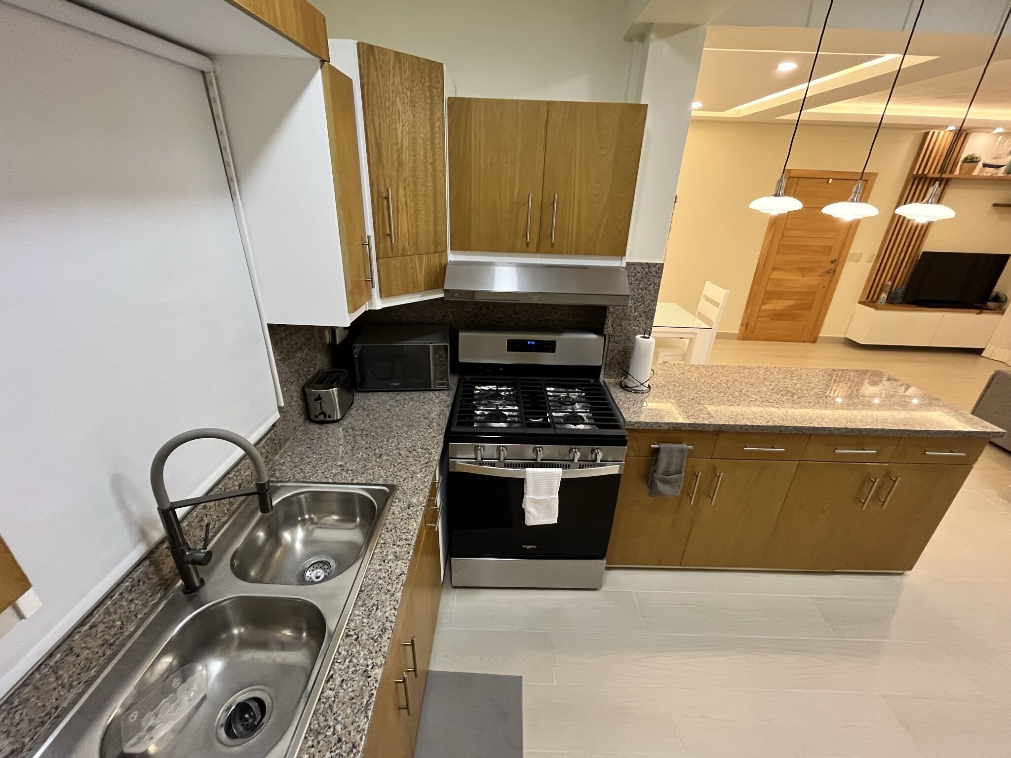 A modern kitchen with stainless steel appliances, wooden cabinets, and a granite countertop.