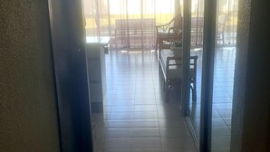A corridor leading to a balcony with tiled flooring, a bench, and a table. - Le grand saint martin II (Marigot)