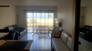 A living room with a sofa, a dining table, and a TV. - Le grand saint martin II (Marigot)