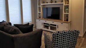 Ein Wohnzimmer mit Flachbildfernseher, weißen Schränken und Deckenventilator.