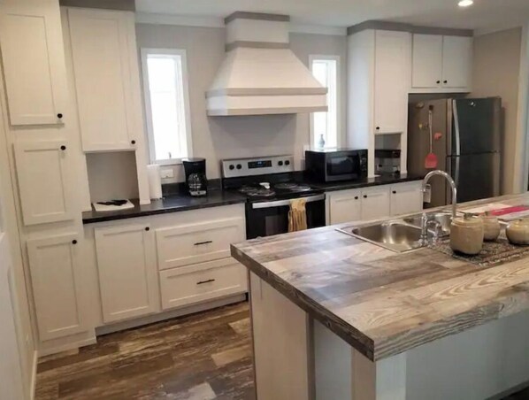 A modern kitchen with white cabinets, a stainless steel refrigerator, a microwave, and a stove. - Home at M&M Meadows (Paris)