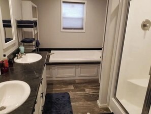 A bathroom with two sinks, a bathtub, a window, and a door. - Home at M&M Meadows (Paris)
