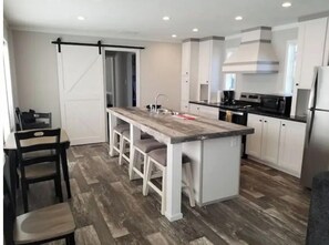 A modern kitchen with a central island, white cabinetry, and a wooden floor. - Home at M&M Meadows (Paris)