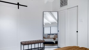 A bedroom with a bed, a bench, a mirror, and a door leading to another room. - Bar, restaurants, and attractions all nearby! (Phoenix)