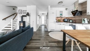 A modern interior with a staircase, a living area with a sofa, a dining table, and a kitchen area.