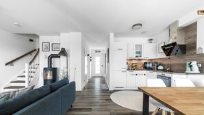 Een modern interieur met een trap, een zithoek met een bank, een eettafel en een keuken.