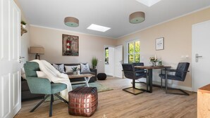 A spacious living room with a sofa, ottoman, and a dining area with chairs and a table. - Ferienwohnung Deck 3 Büsum (Büsum)