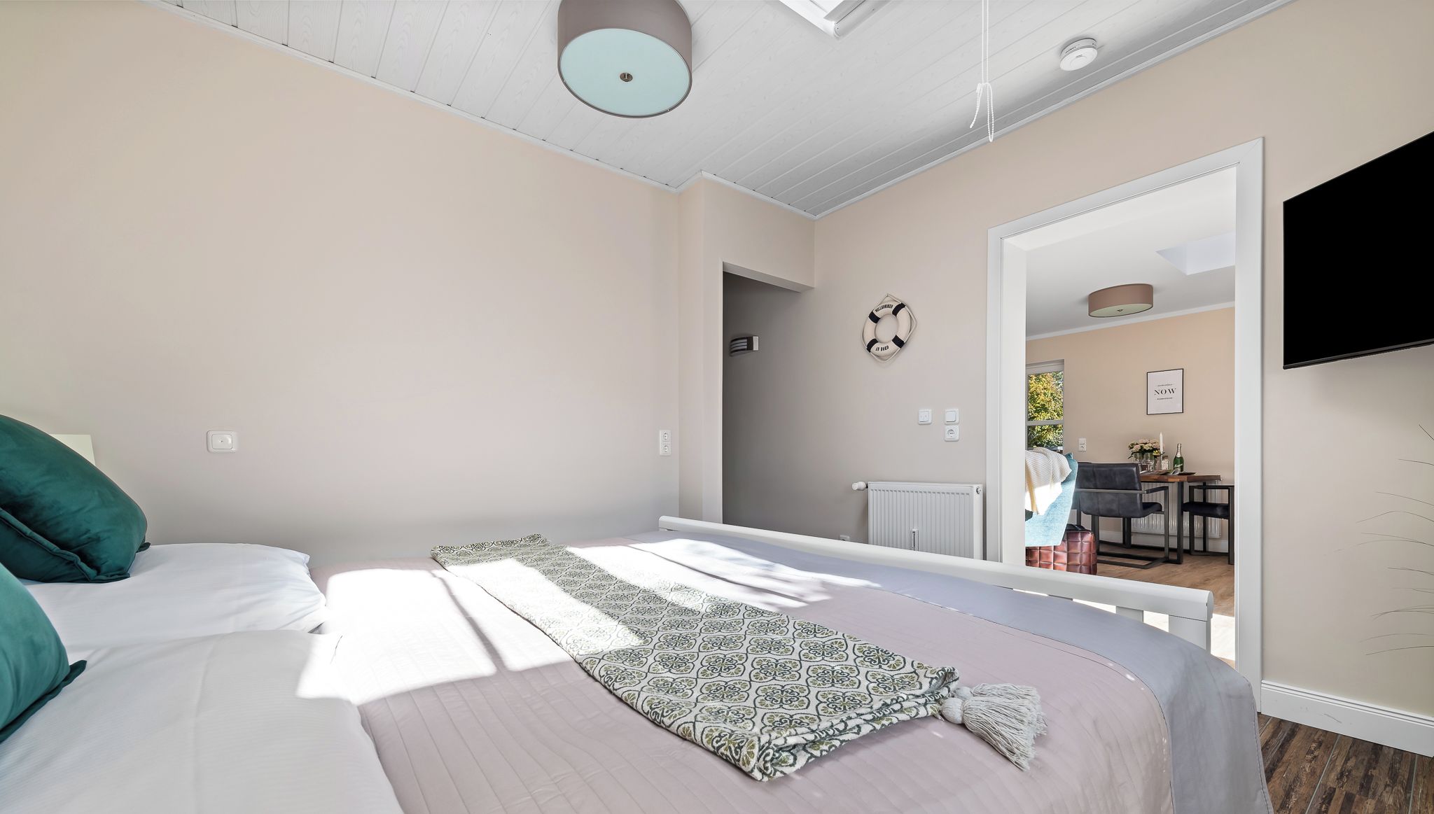 Un dormitorio con cama, mesita de noche, televisor y vista al comedor.