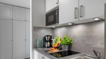 Une cuisine moderne dotée d’un four à micro-ondes encastré, d’un évier en acier inoxydable et d’une plaque de cuisson à induction noire.