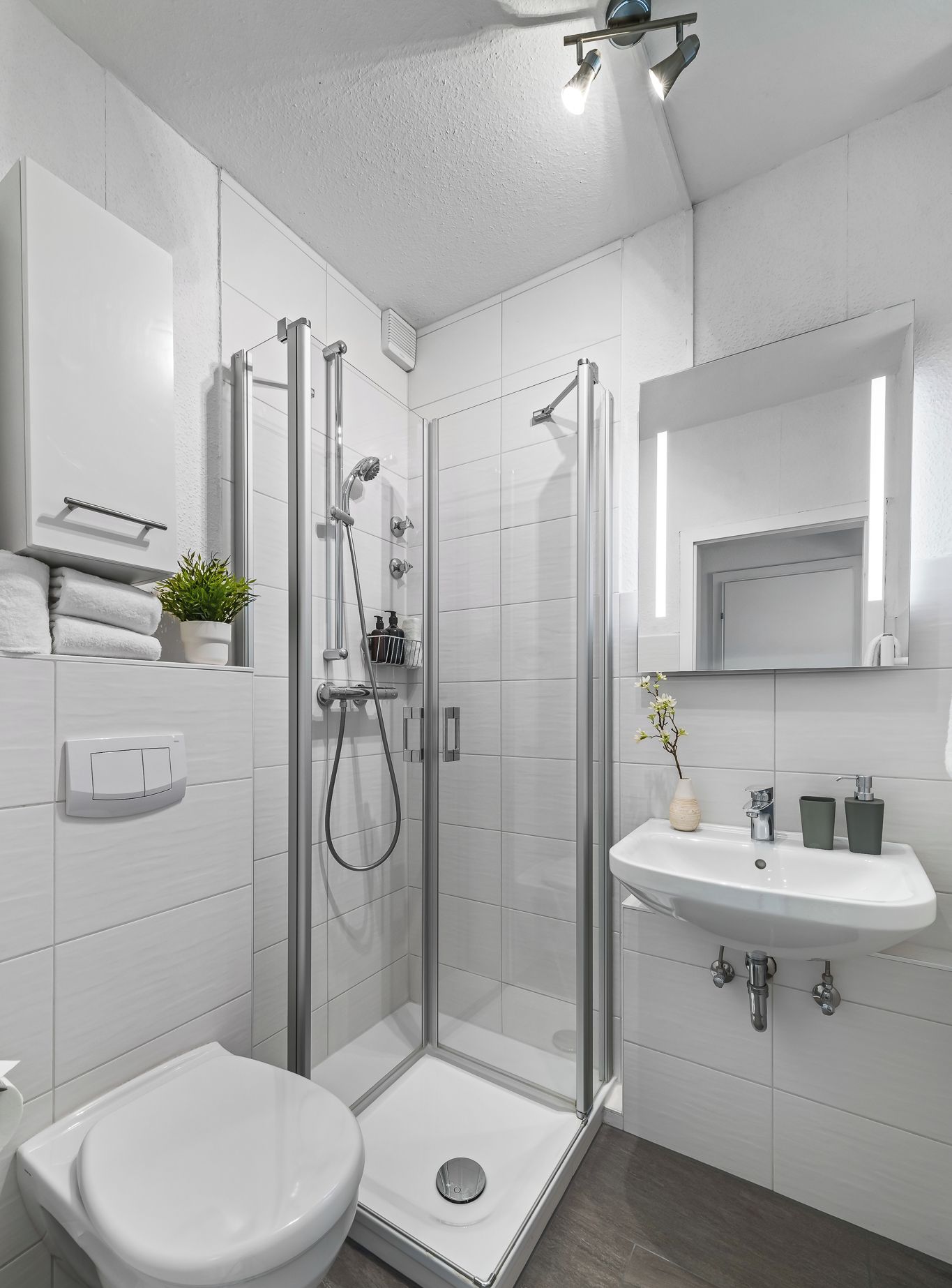 Un bagno moderno con doccia vetrata, un water bianco, un lavandino e uno specchio.