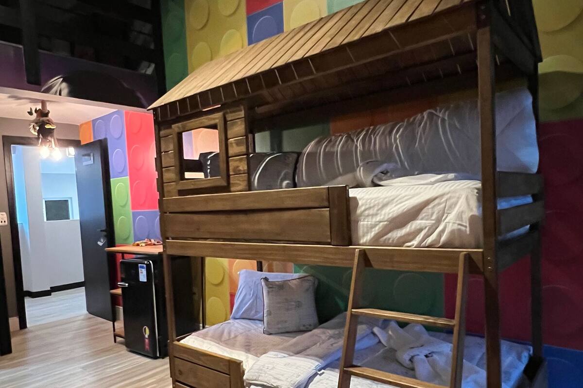 A bunk bed with a wooden frame and a colorful wall behind it.