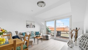 Ein modernes Wohnzimmer mit Essbereich, großen Fenstern und Blick auf die Stadt.