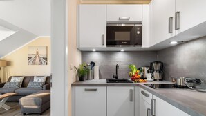 Una cucina moderna con mobili bianchi, un microonde Bosch e una macchina per il caffè.