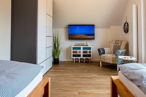 A cozy room with a bed, a chair, a TV, and a small table. - Ferienhaus Tweete Heimaat Büsum (Büsum)