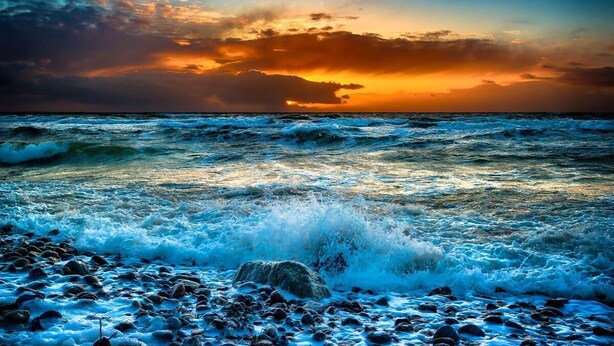 A beach with waves crashing onto the shore and a sunset in the background. - Suutje Bude - for 4 persons, terrace, quiet location (Büsum)