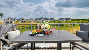 En terrasse med spisebord og stole i flet, med udsigt til huse i baggrunden.