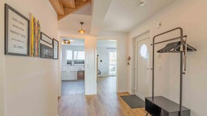 A hallway with wooden flooring, a coat rack, and framed artwork on the walls. - Gode Tied - Fireplace, Infrared Sauna, Bathtub, Shower, Balcony, Parking Space (Olpenitz)