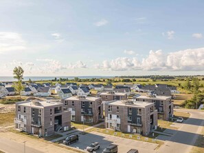 Un complexe résidentiel moderne composé de plusieurs immeubles à deux étages, chacun doté de balcons et d’une cour intérieure.
