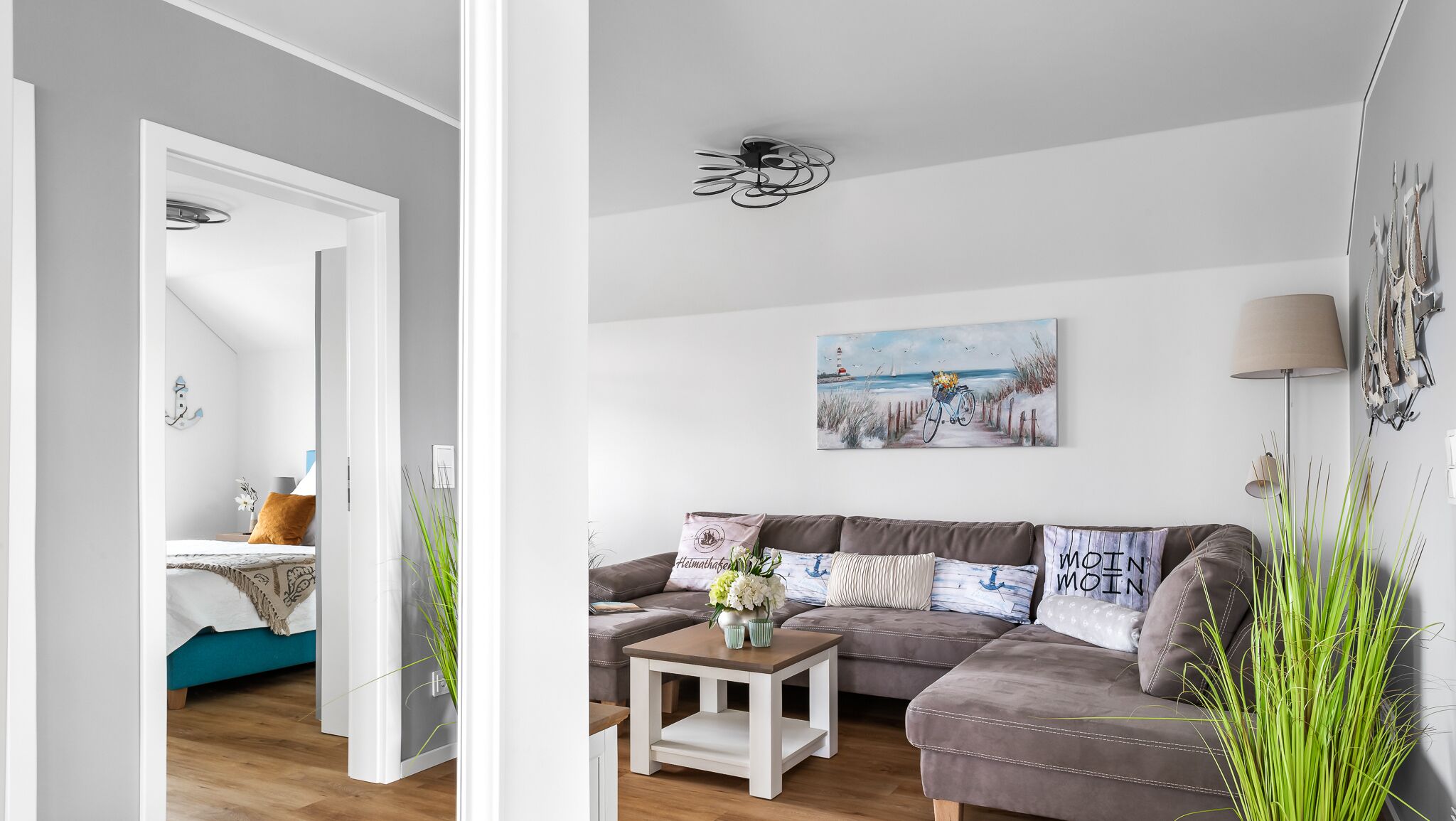 Ein modernes Wohnzimmer mit einer Couch, einem Couchtisch und einem Strandbild.