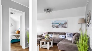 Una sala de estar moderna con un sofá, una mesa de centro y un cuadro de una escena de playa.