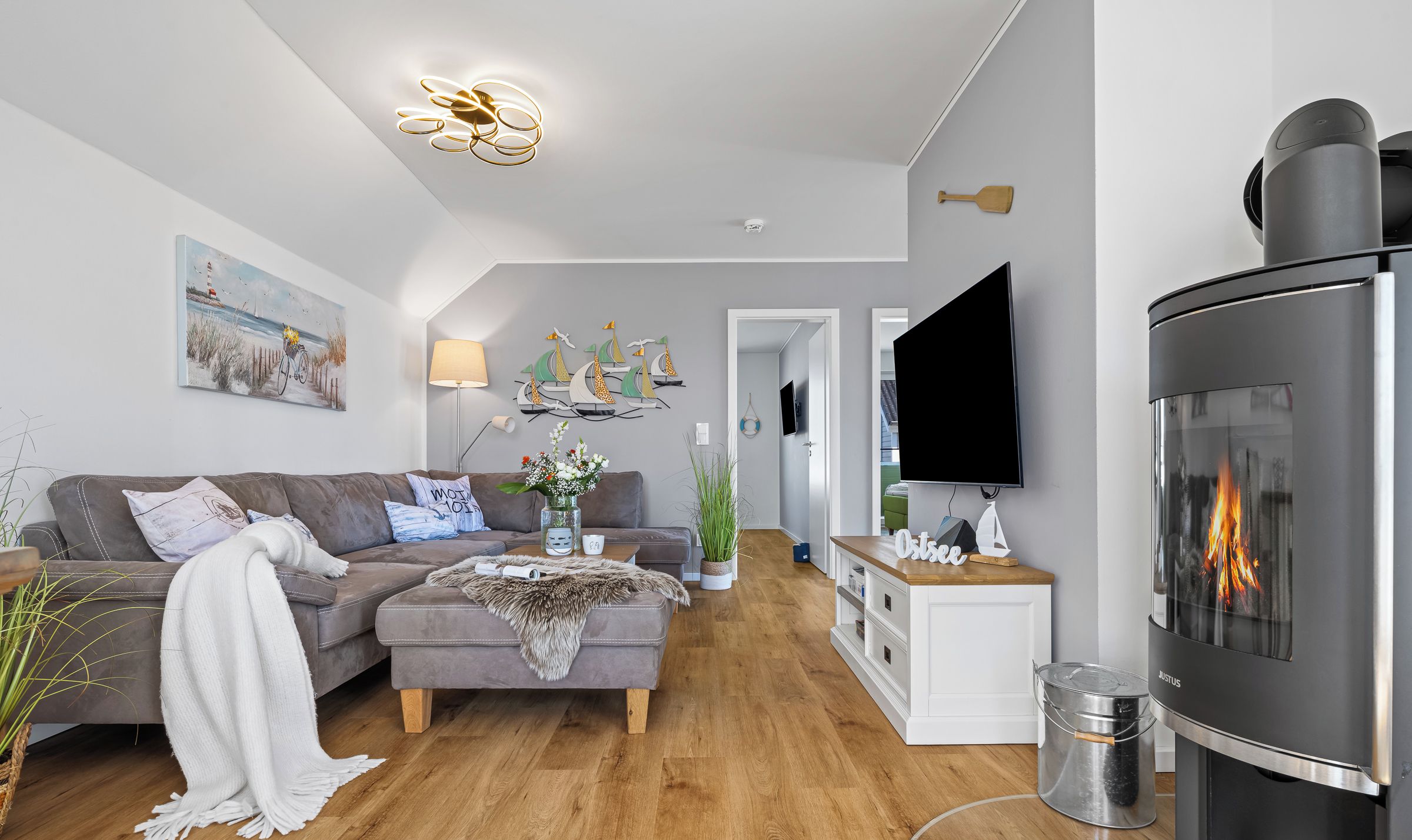 Ein modernes Wohnzimmer mit Kamin, einer Couch, einem Couchtisch und einem an der Wand befestigten Fernseher.