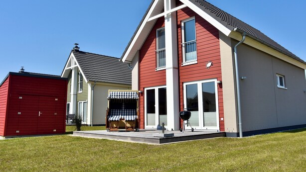 Ett modernt hus i två våningar med en röd fasad, en täckt uteplats och ett garage.